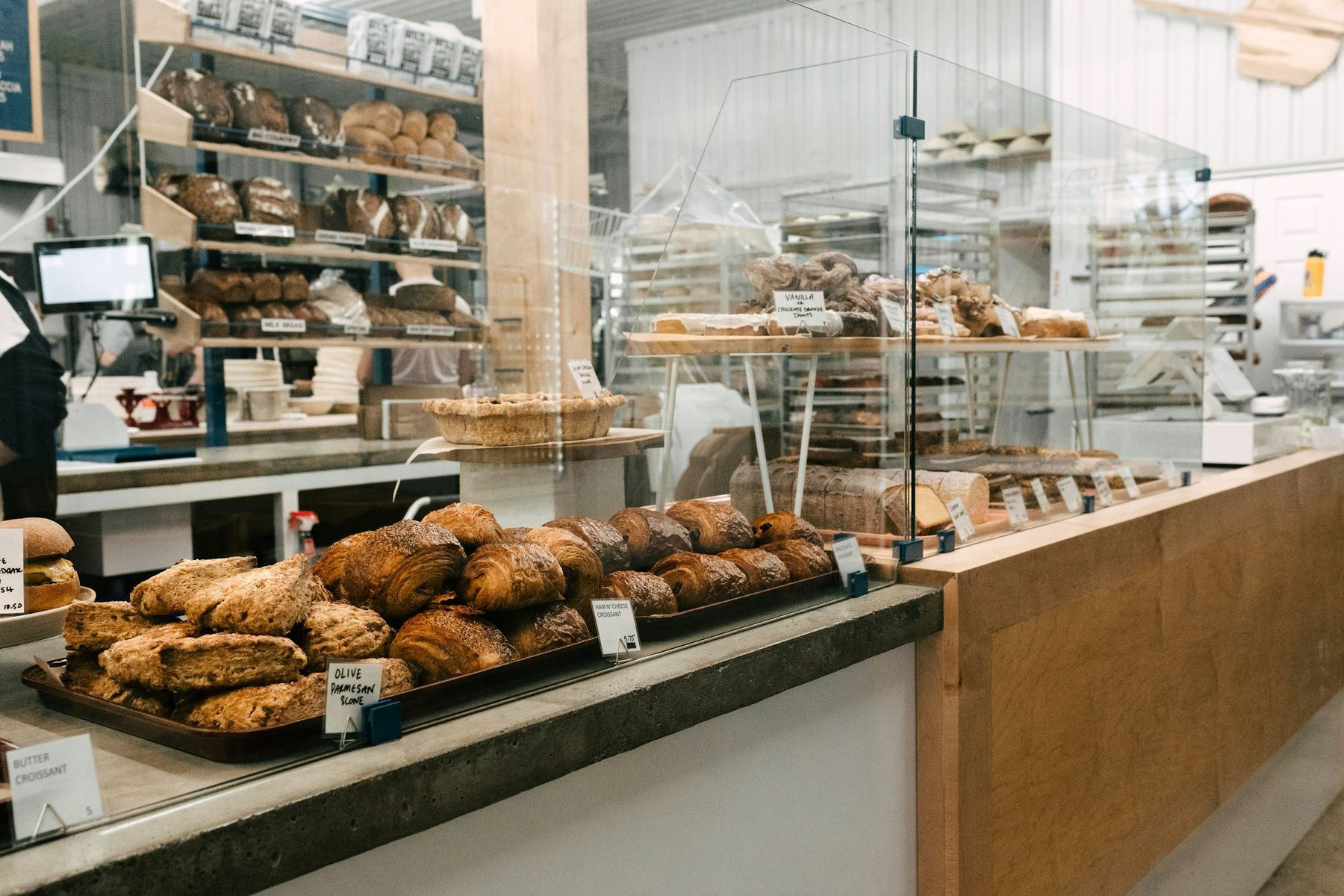 Le comptoir de la boutique : croissants et pains sur les plateaux, vitrines de viennoiseries.