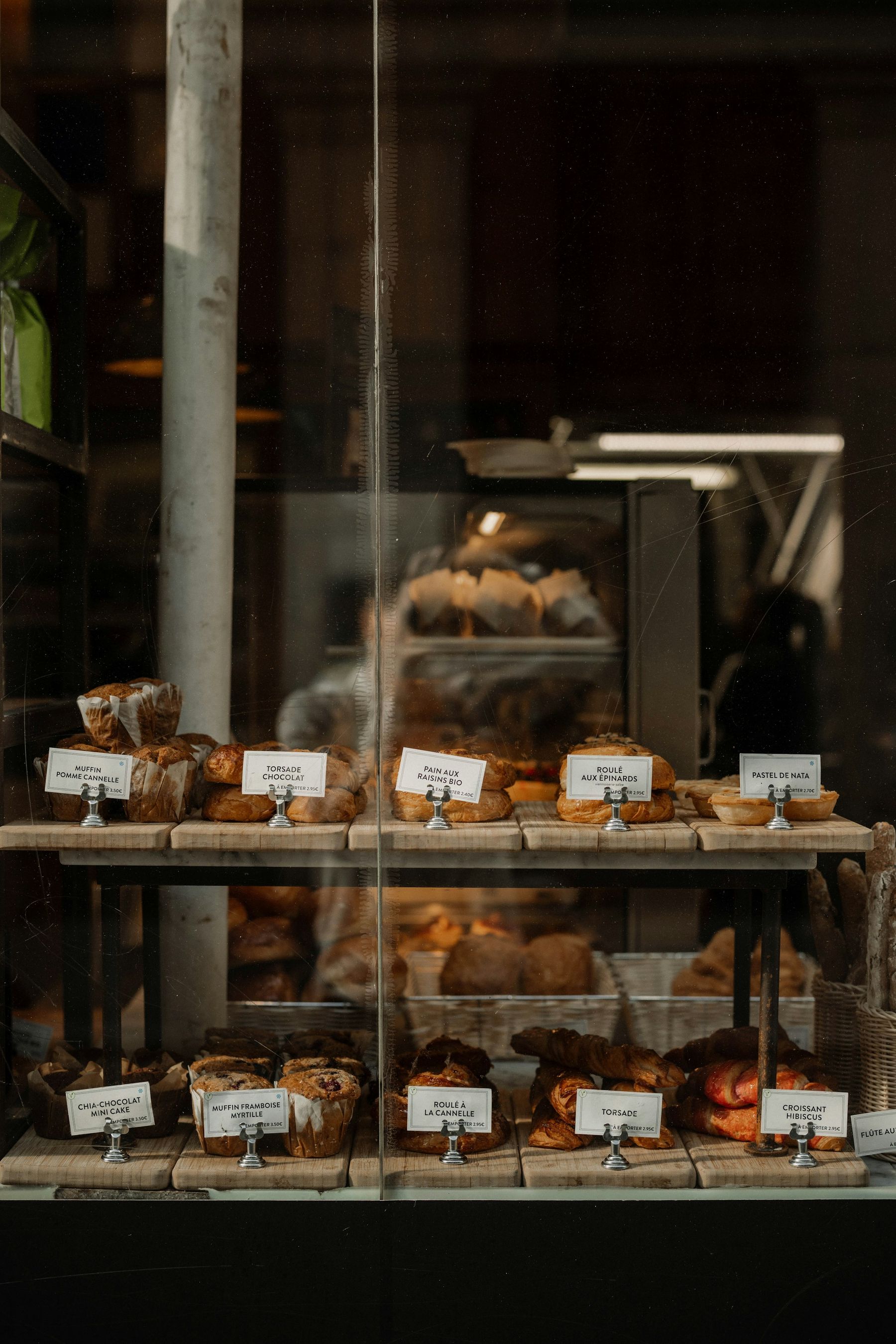 La vitrine de la boutique, garnie de pâtisseries et de viennoiseries étiquetées.